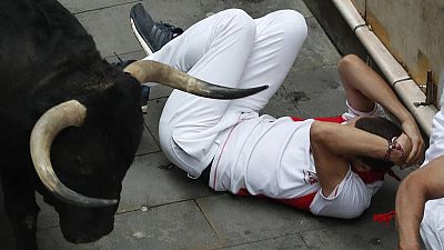Un mozo se protege de un toro en la calle Estafeta