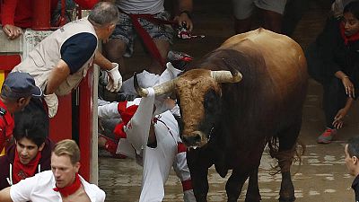 El toro Huracán empitona a un mozo en el cajellón de la plaza de Pamplona