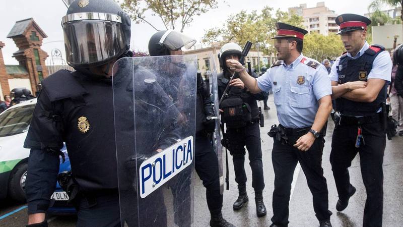 Agentes antidisturbios de la Policía Nacional y de los Mossos d' Esquadra discuten frente al Instituto Can Vilumara de L'Hospitalet de Llobregat