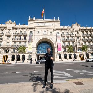 Cultura con Ñ - El arquitecto David Chipperfield posa frente a la sede del Banco Santander en Santander, con las palabras "BUS", "TAXI" y "MOTO" pintadas en el asfalto ante él.