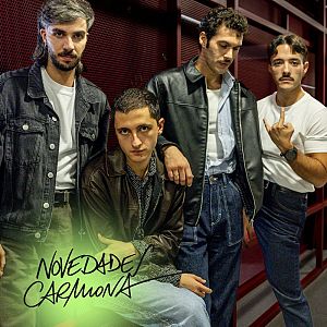 Novedades Carmona - Plano medio de los cuatro integrantes del grupo Carolina Durante posando juntos frente a una pared de rejilla metálica roja.