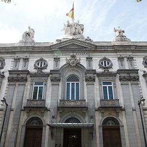 Hora América - Vista frontal de la fachada neoclásica del Tribunal Supremo en Madrid con esculturas, grandes portalones y una bandera ondeando en el tejado.