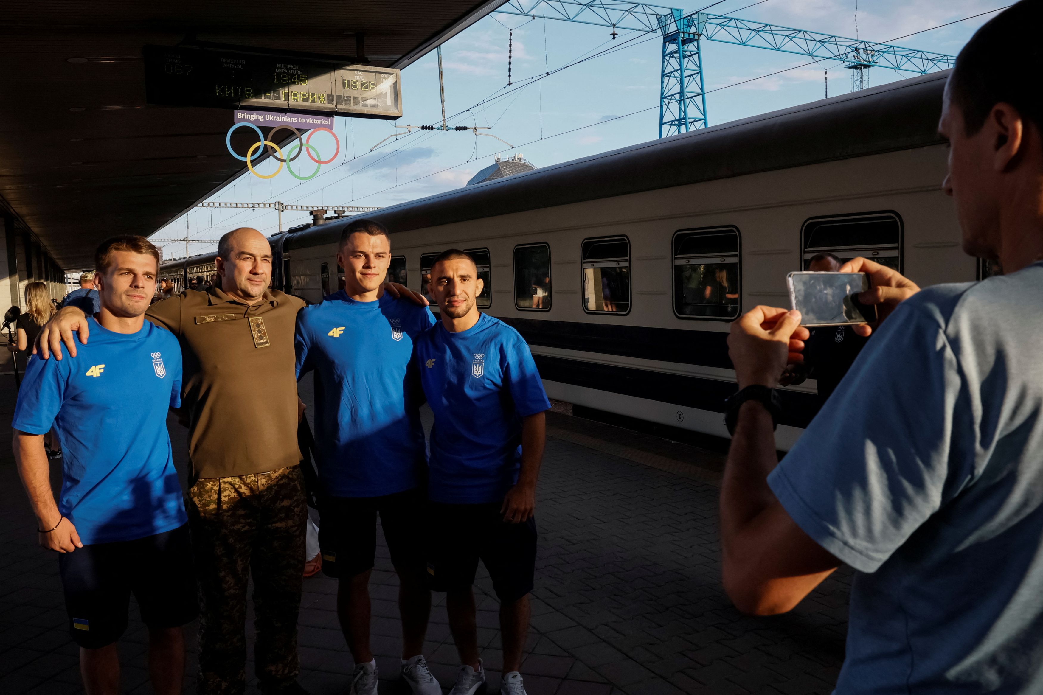 Miembros del equipo olímpico ucraniano posan con un familiares del ejército, antes de subir a un tren con destino a París