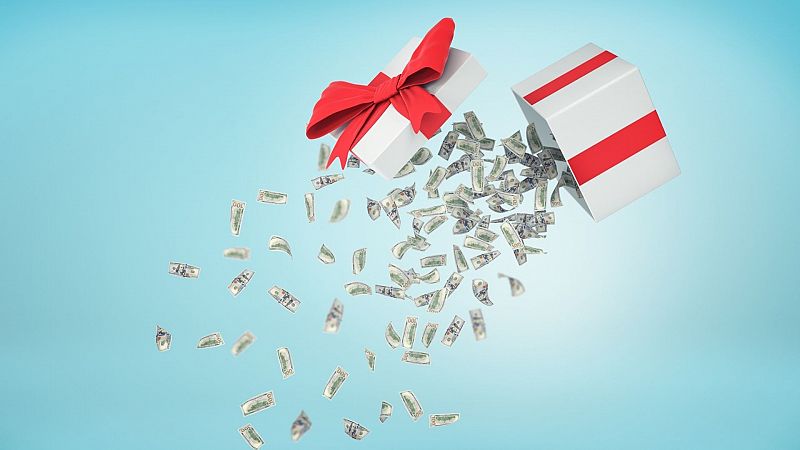 Un regalo de Navidad blanco con un lazo rojo se abre y de él caen billetes de dinero
