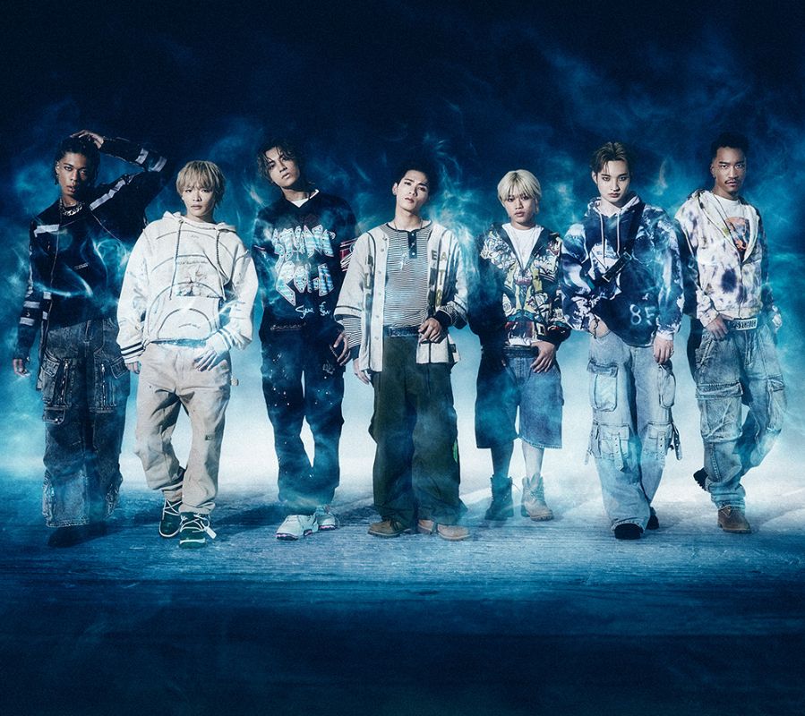 Siete jóvenes con ropa urbana posan sobre una superficie reflectante con fondo oscuro y humo azul.  Aparece el texto "Psychic Fever" y "Secciones".