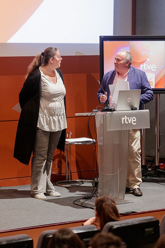 Gala de bienvenida: presentadora con blusa clara y pantalones grises, hombre con camisa azul hablando, pantalla con logo RTVE y nombre del programa.