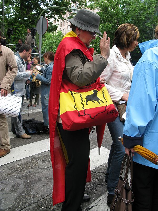 Con una bandera española y un bolso a juego.