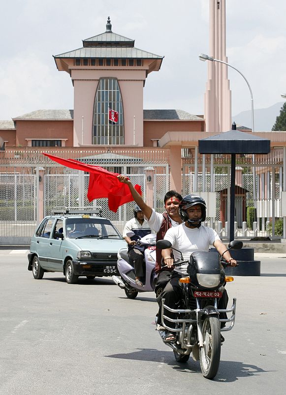 Un motorista ondea una bandera frente al palacio real de Nepal.