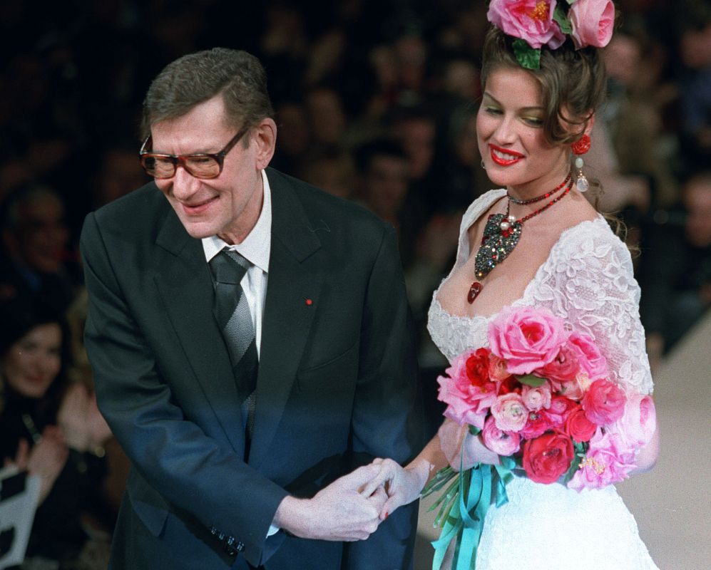 El diseñador Yves Saint Laurent despide un desfile con la modelo Laetitia Casta en el año 1998 en París.