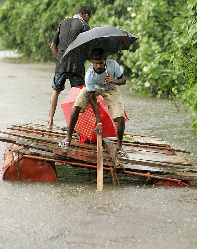 Dos ciudadanos intentan escapar de las inundaciones que han causado las fuertes lluvias en gran parte de Sri Lanka. Las lluvias torrenciales han dejado al menos 16 muertos y miles de desplazados.