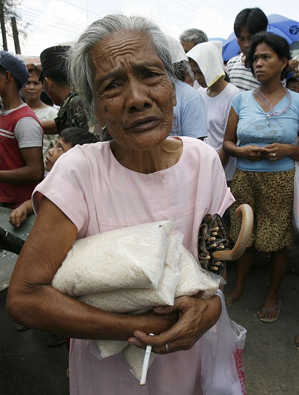Una mujer recoge varios paquetes de arroz subvencionados por el Gobierno en Manila.