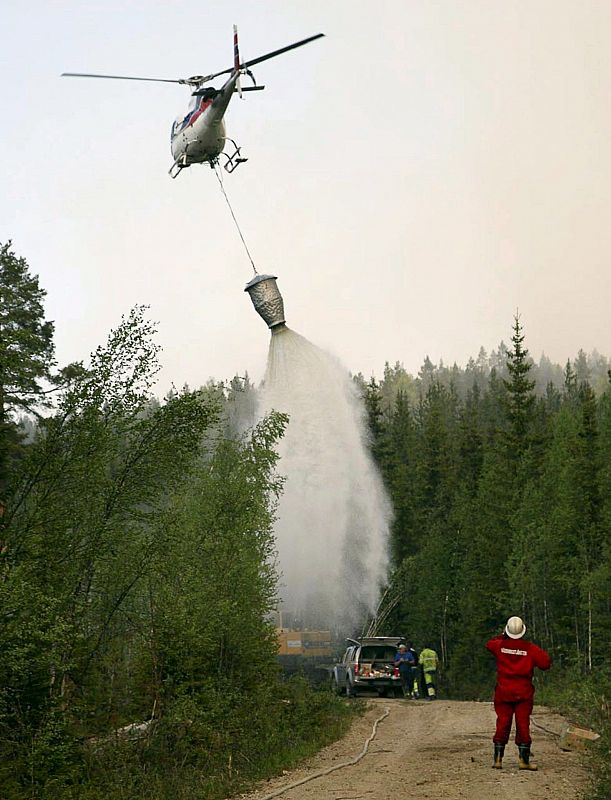 Un helicóptero trata de apagar un incendio en el bosque de la localidad de Hassela, al norte de Suecia. Siete helicópteros y alrededor de 200 bomberos, voluntarios y soldados del ejército están tratando de apagar el fuego.