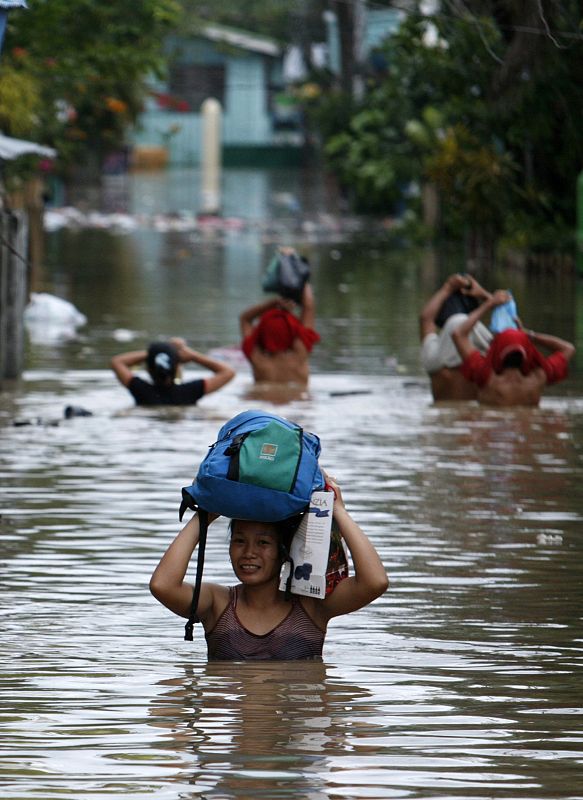 Los residentes de la ciudad de Zamboanga, al sur de Filipinas,  caminan entre el agua que les llega al pecho intentando salvar sus enseres