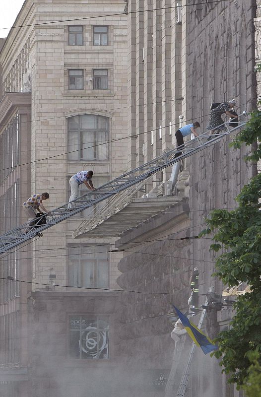 Un grupo de personas desciende por una escalera de un camión de bomberos para escapar del incendio que se declaró en la sede del departamento de Arquitectura, Planificación y Diseño Urbano de la ciudad de Kiev. El fuego se originó por cortocircuito.