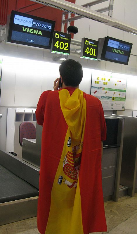 Un aficionado de la 'Roja', atento a los mostradores de facturación en la Terminal 2 del aeropuerto de Barajas.