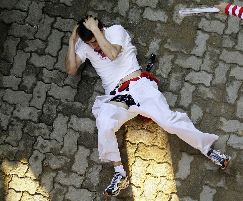 A fallen runner reacts after bull stepped on him and ripped his pants during fourth bull run of San Fermin festival in Pamplona