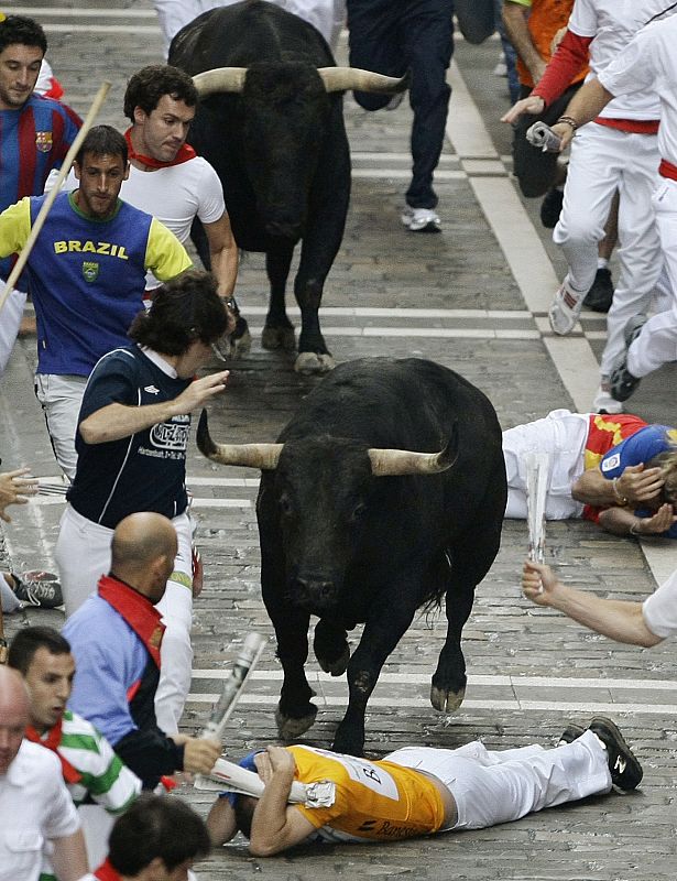 A fallen runner lies in path of bulls during the fifth running of the bulls of San Fermin festival in Pamplona