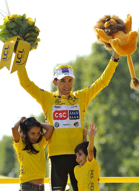 Sastre celebra su victoria sobre el podio junto a sus hijos, Claudia (izda) y Yeray (dcha), al término de la última etapa del Tour de Francia.