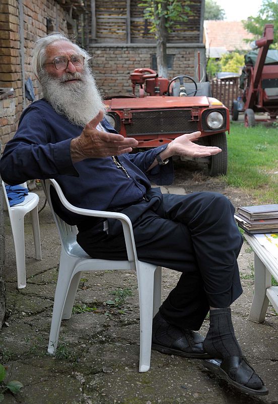 Petar Glumac alternative medicine healer sits in front of his house in the village of Banatsko Novo Selo