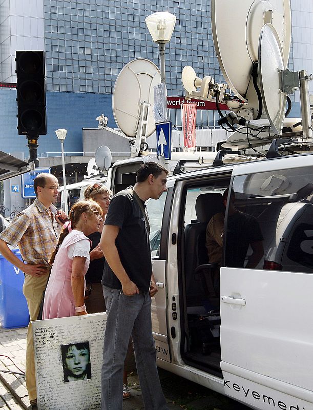 Un grupo de curiosos observa la comparecencia desde una unidad móvil