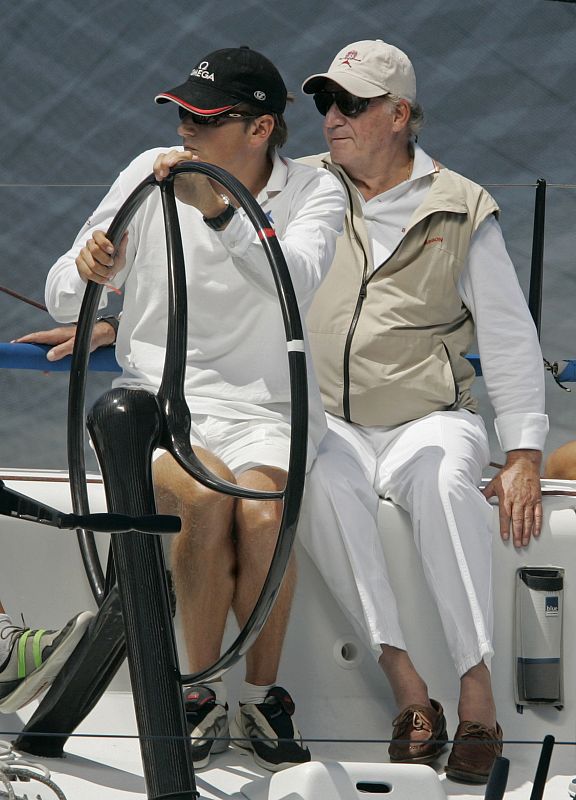 Spain's King Carlos sits next to helmsman Baker as they compete during the 27th King's Cup sailing race in Mallorca