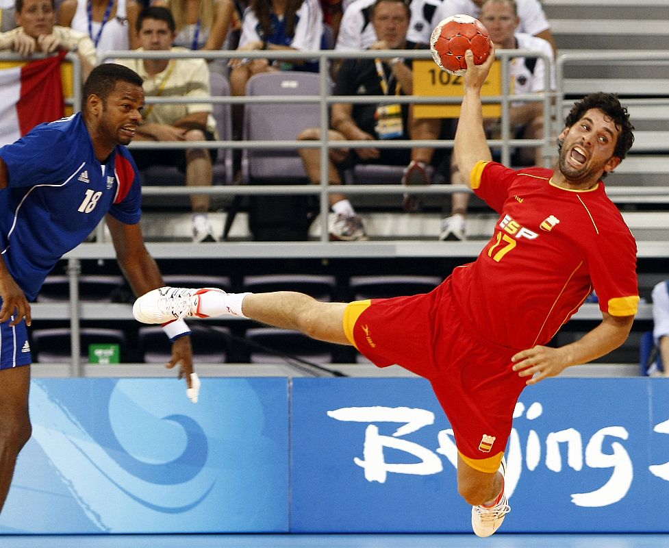 El español Juan García intenta lanzar el balón al superar al francés Joel Abati en el partido de primera ronda de balonmano que ha perdido España.