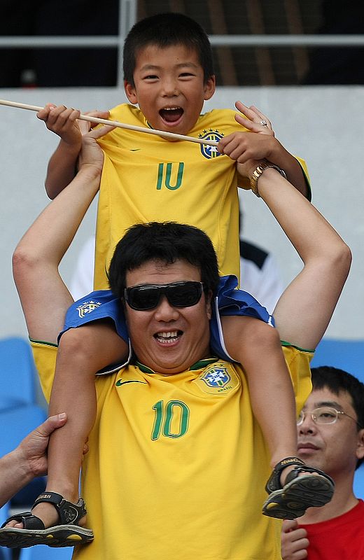 Un aficionado chino y su hijo esperan el inicio del partido Brasil-Camerún de cuartos de final.