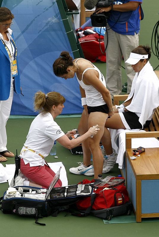 La española Virginia Ruano es atendida por un fisioterapéuta en presencia de una juez de pista ,durante la final de dobles femeninos de tenis.