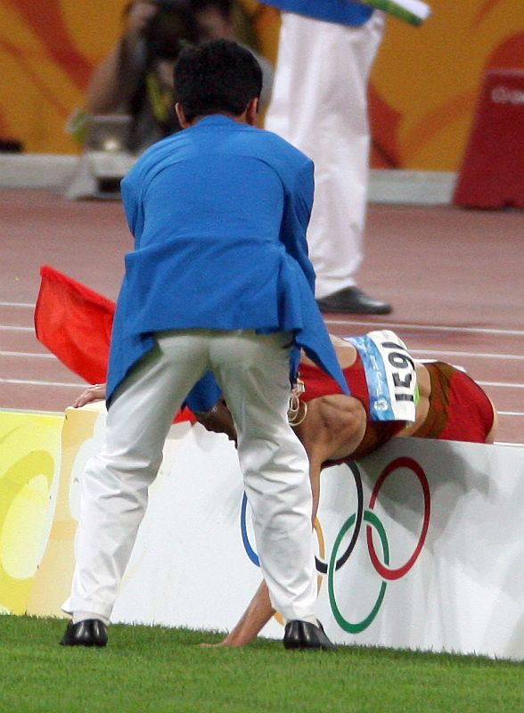 La española Marta Dominguez recibe ayuda tras caerse a media vuelta de la final de los 3.000 metros obstáculos femeninos cuando luchaba junto a la keniana Eunice Jepkorir y la rusa Yekaterina Volkova por la medalla de plata.