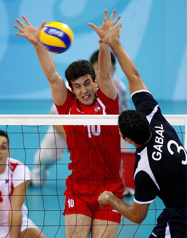 El egipcio Mohamed Gabal golpea el balón contra el serbio Milos Nikic durante la preliminar masculina del grupo B del torneo de voleibol.