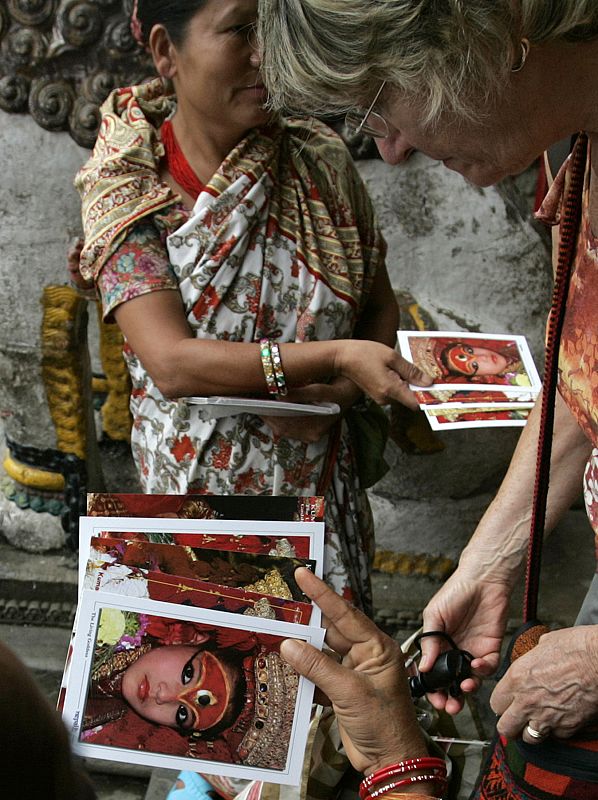 El fenómeno de las niñas-diosas se ha convertido en un gran atractivo turístico. En la foto, una mujer nepalesa muestra postales de la 'kumari' de Basantapur, en Kathmandu.