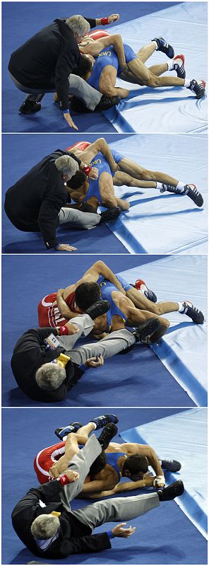 Kanatbek Begaliev of Krygyzstan and Armen Vardanyan of Ukraine crash into referee Lee Ronald Mackay during their men's 66kg Greco-Roman quarter-final wrestling match at the Beijing 2008 Olympic Games