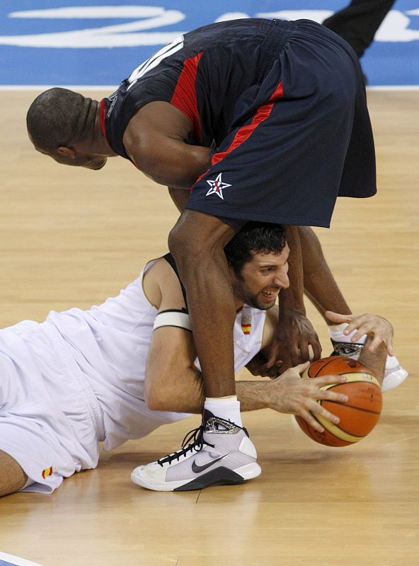 El jugador Alex Mumbru (en el suelo) lucha por el balón con el estadounidense Kobe Bryant.