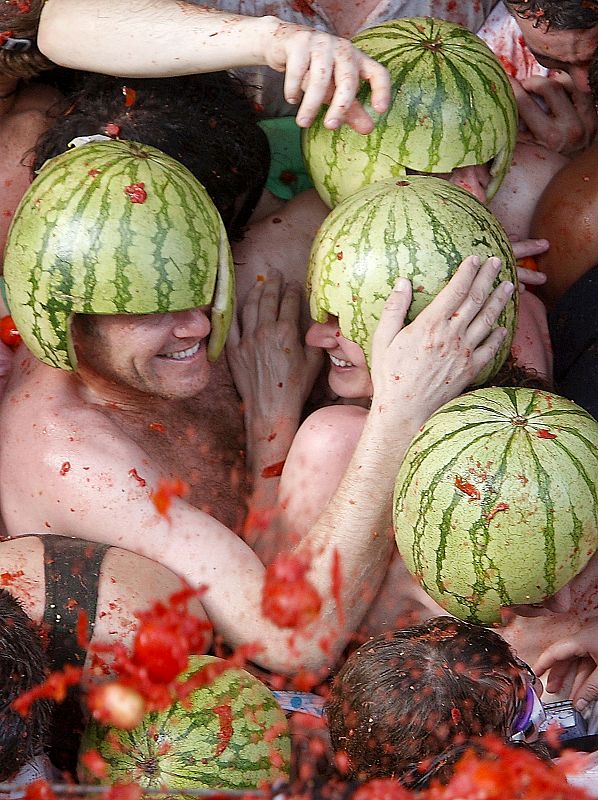 Varios jóvenes utilizan las cáscaras de sandía como cascos para protegerse de los tomates que han volado por los aires de Buñol, una tradición que se repite desde hace 63 años el último miércoles de cada agosto.