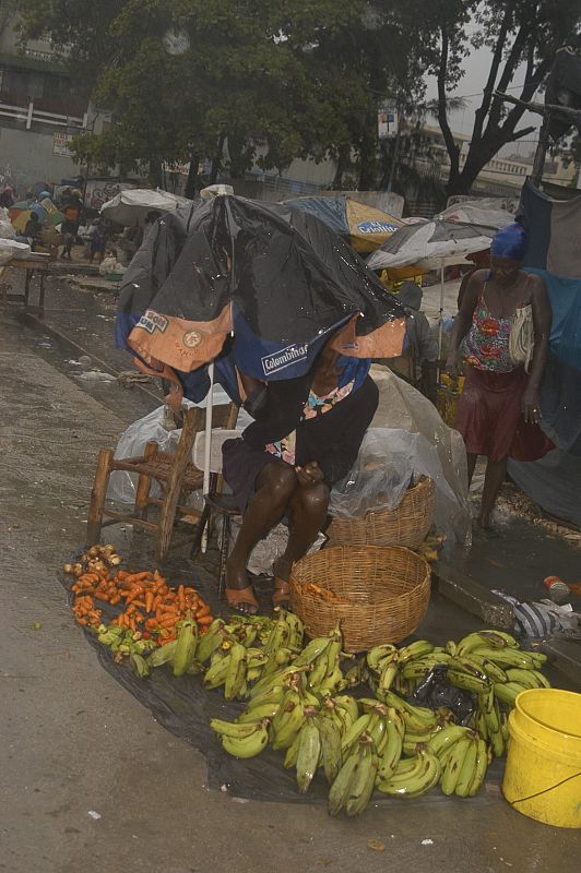 Las vendedoras ambulantes se protegen de la lluvia en la localidad haitiana de Bicentenaire, donde se han registrado vientos de 150 kilómetros por hora.