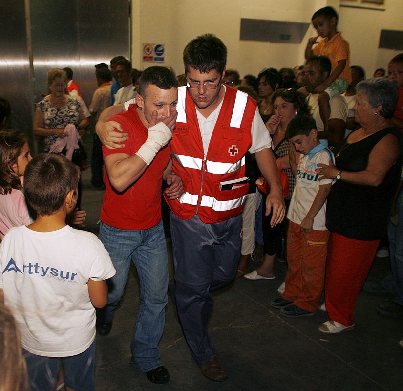 A relative of a dead fisherman and a Red Cross member leave a fish market in Barbate