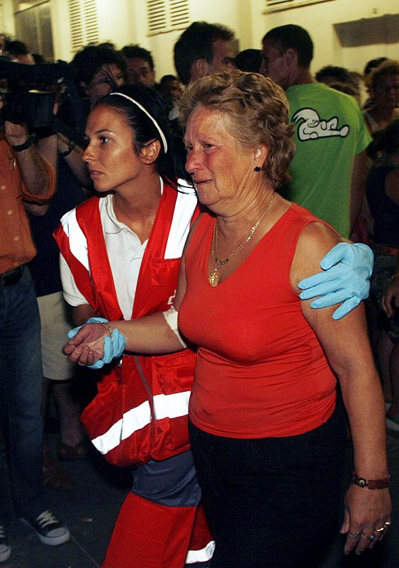 A relative of a dead fisherman and a Red Cross member leave a fish market in Barbate