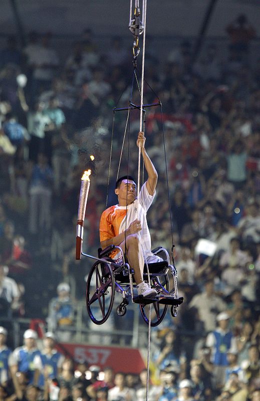 El atleta chino Hou Bin ha sido el encargado de encender la llama olímpica, subiendo a pulso por la cuerda que le llevaba al pebetero.