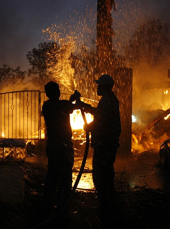 Residents help with garden hoses as a neighbor's home burns to the ground in Yorba Linda, California