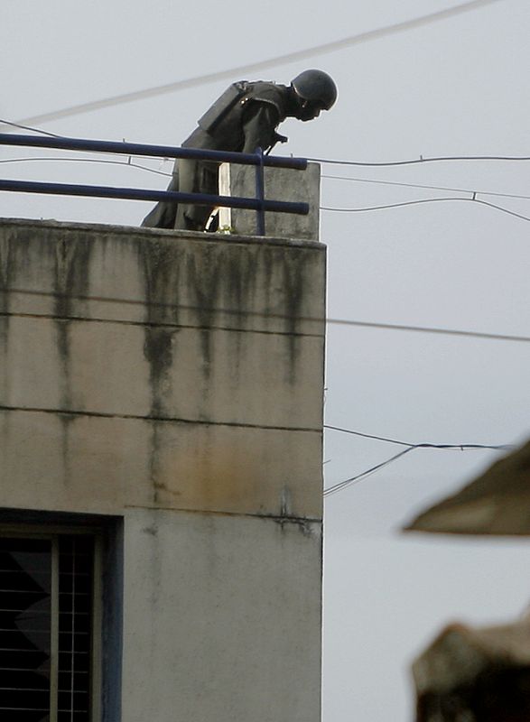 Un comando NSG mira en la azotea de un edificio en Bombai en el cual se ocultan los militantes sospechados.