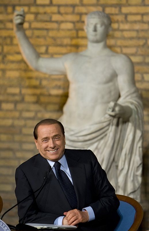 Italy's Prime Minister Berlusconi smiles as he leads a meeting to unveil the logo of the next G8 summit in downtown Rome
