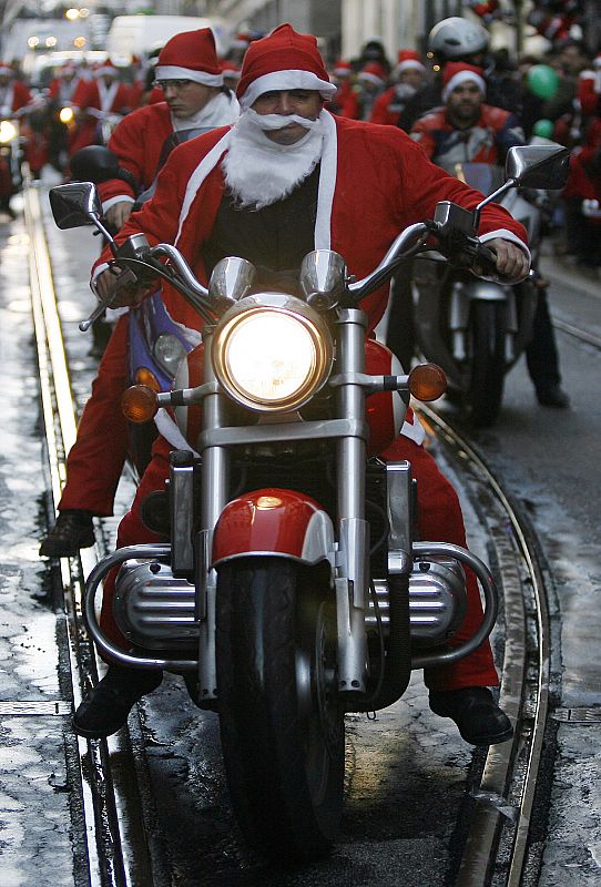 Men dressed in Santa Claus costumes ride on motorbikes during a parade in the streets of Porto