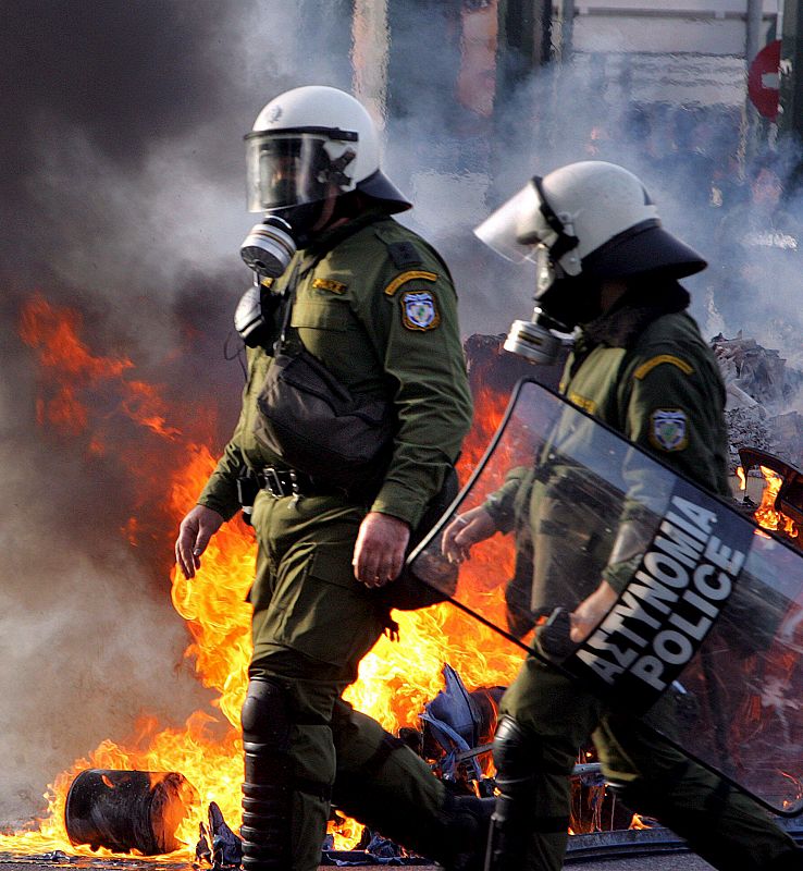 Policías griegos pasan junto a un contenedor en llamas durante los enfrentamientos