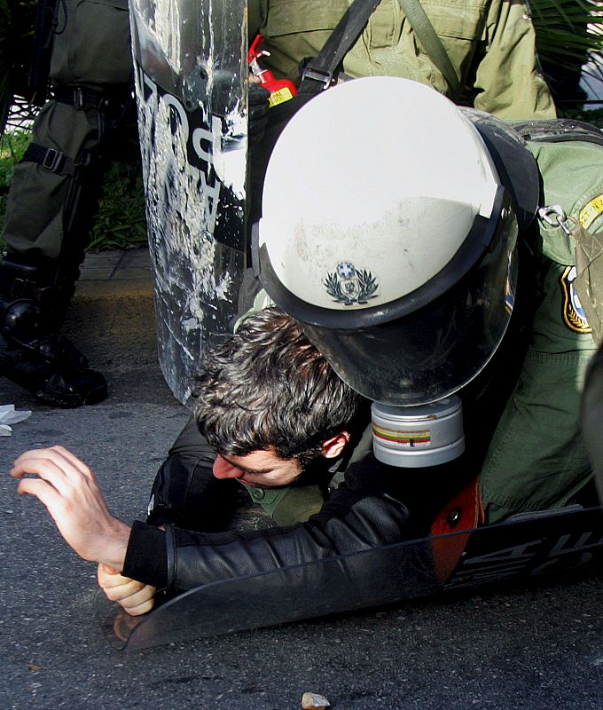 Agentes antidisturbios arrestan a un manifestante frente a la sede central de la policía en Atenas.