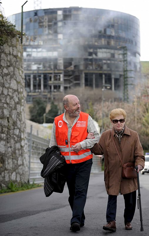 Una señora es asistida por un empleado de los servicios municipales, tras la explosión de un artefacto junto a la sede de la Televisión autonómica del País Vasco, EITB, en el centro de Bilbao.