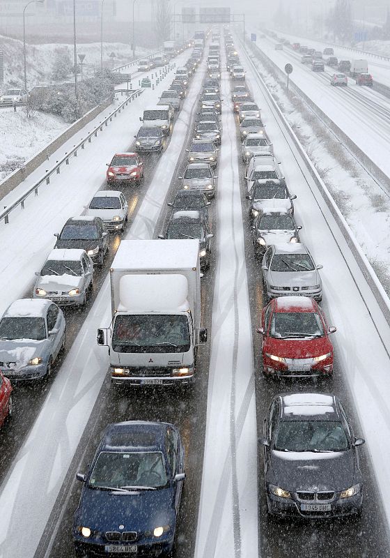 Numerosos vehículos permanecen atascados en uno de los sentidos de la M-40 de Madrid, que permanece parcialmente cerrada al tráfico debido a la intensa nevada que cae hoy sobre la ciudad.