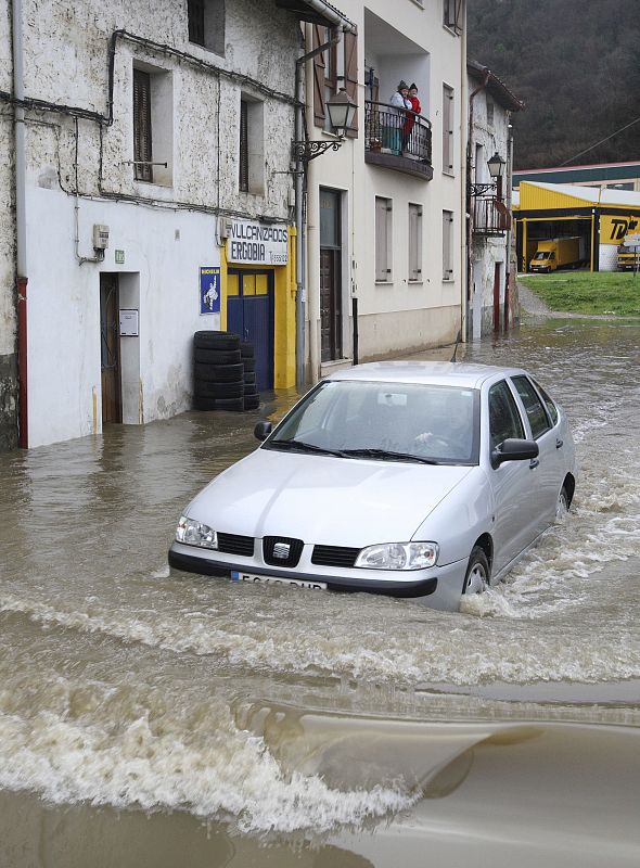 Un conductor circula por una de las zonas inundadas en Ergobia. El agua ha llegado a la altura de los motores.
