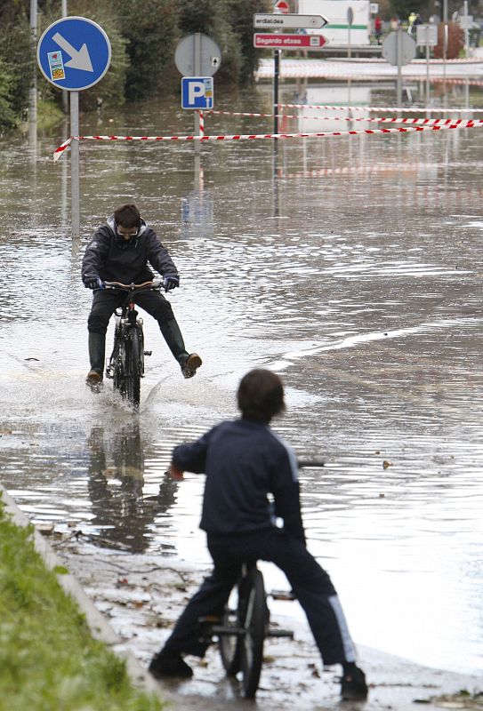 Dos chavales juegan hoy con las bicis en el municipio guipuzcoano de Astigarraga, inundado en algunas zonas tras las fuertes lluvias caídas desde ayer en la región.