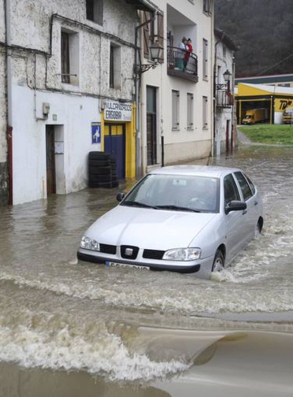 Un conductor circula por una de las zonas inundadas en Ergobia. El agua ha llegado a la altura de los motores. 