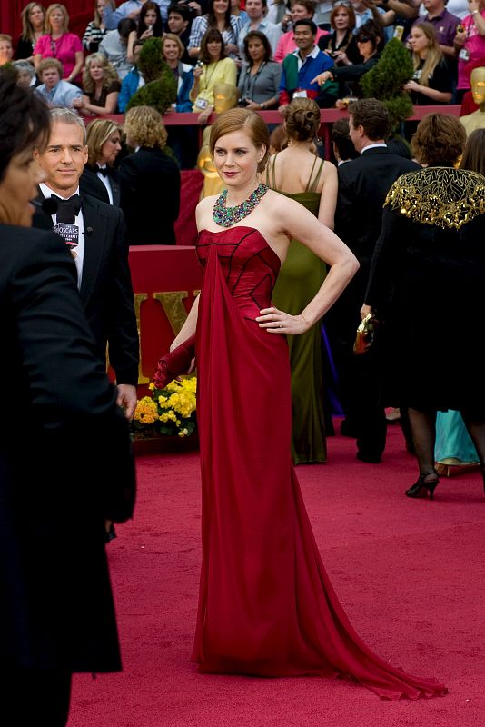 Amy Adams posa con un vestido rojo intenso y un llamativo collar multicolor.